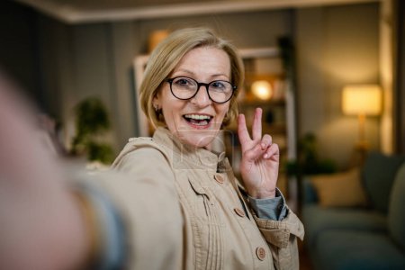 Photo for Portrait of one mature blonde caucasian woman with eyeglasses at home happy smile looking to the camera confident wear shirt copy space - Royalty Free Image