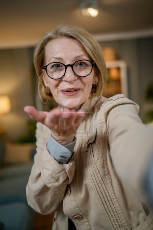 Téléchargez les photos : Portrait d'une femme caucasienne blonde mature avec des lunettes à la maison sourire heureux regardant vers l'appareil photo confiant porter l'espace de copie de chemise - en image libre de droit