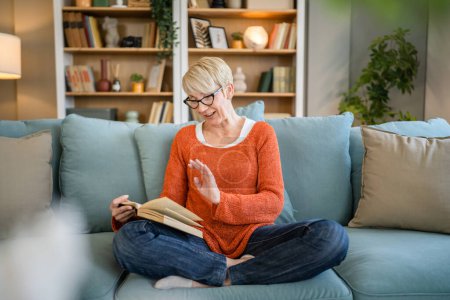 Eine Frau reif Senior kaukasischen Rentnerin moderne Großmutter mit kurzen Haaren lesen Buch zu Hause tragen Brille echte Person Kopierraum