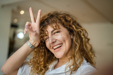 Téléchargez les photos : Une femme caucasienne heureuse confiance stand intérieur au café avec des cheveux bouclés sourire personne réelle copie espace autoportrait selfie UGC User Generated Content - en image libre de droit