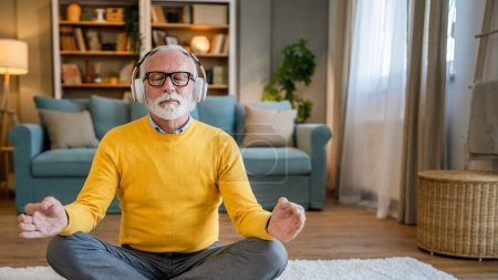 Foto de Un hombre adulto mayor caucásico masculino usando auriculares para la meditación guiada en línea practicando mindfulness manifestación de yoga con los ojos cerrados en casa personas reales autocuidado concepto copia espacio - Imagen libre de derechos