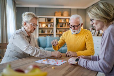 Photo for Group of senior people man and woman husband and wife friends or family play leisure board game at home have fun pensioner grandfather and grandmother spend time together with their mature daughter - Royalty Free Image