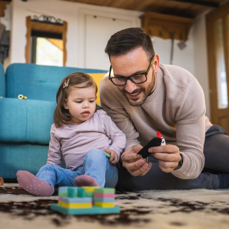 Photo for Father and daughter on the floor at home mature adult caucasian man play with finger puppets with his two years old child toddler girl having fun parenting and bonding family time concept copy space - Royalty Free Image