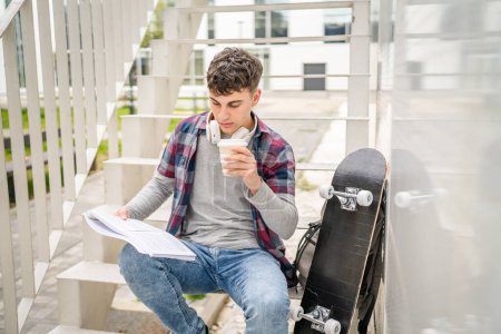 Téléchargez les photos : Un jeune homme adolescent étudiant caucasien avec des livres lire étude sur le campus dans la journée assis sur escalier éducation concept copier l'espace - en image libre de droit
