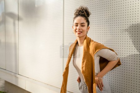 Téléchargez les photos : Une femme jeune adulte caucasien femelle debout extérieur posant portrait heureux confiant en face de blanc mur copier l'espace - en image libre de droit