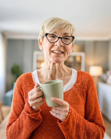 Photo for Close up portrait of one senior woman with short hair happy smile positive emotion copy space standing at home indoor wear eyeglasses have a cup of coffee daily morning routine - Royalty Free Image