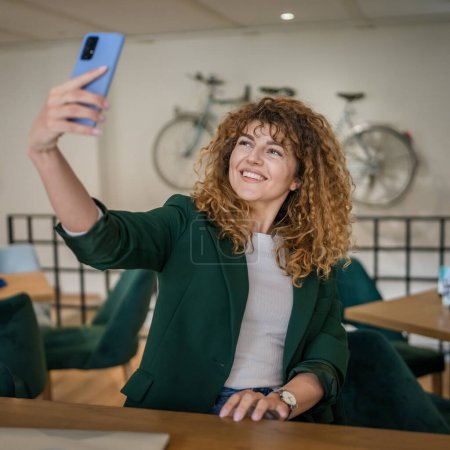 Photo for One woman adult caucasian female sit at cafe use phone smartphone for online internet video call or self portrait selfie happy smile confident smiling real person receive good news copy space - Royalty Free Image