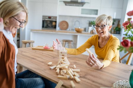 Téléchargez les photos : Deux femmes âgées femmes amies ou sœurs de la famille jouent jeu de société de loisirs à la maison ont plaisir retraité grand-mère passer du temps avec leur fille mature - en image libre de droit