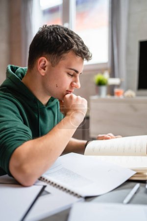Photo for One young man caucasian teenager student learning study reading book while sitting at home prepare exam or work on project real people education concept copy space - Royalty Free Image