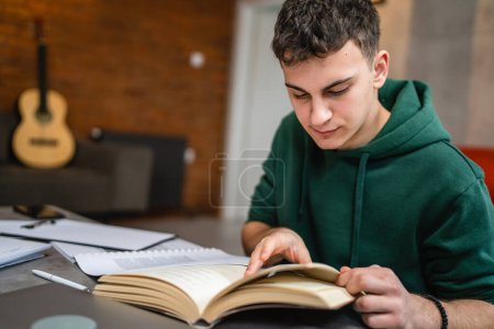 Téléchargez les photos : One young man caucasian teenager student learning study reading book while sitting at home prepare exam or work on project real people education concept copy space - en image libre de droit