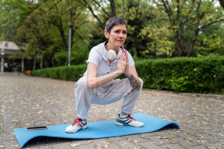 Téléchargez les photos : Une femme caucasienne mature pratique le yoga en plein air - en image libre de droit
