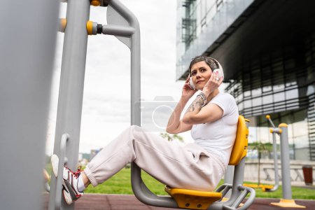 Foto de Una mujer madura o mayor caucásica entrenamiento femenino en la prensa de piernas máquina de fitness urbana en el parque en el gimnasio al aire libre Deporte concepto de estilo de vida saludable personas reales copiar espacio - Imagen libre de derechos
