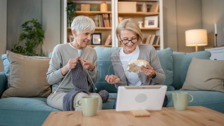 Photo for Two women senior mature caucasian friends or mother and daughter or sisters knitting and embroidery during leisure time at home needlework concept happy and relaxed enjoy free time - Royalty Free Image