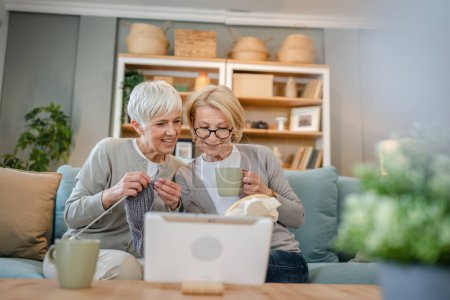 Photo for Two women senior mature caucasian friends or mother and daughter or sisters knitting and embroidery during leisure time at home needlework concept happy and relaxed enjoy free time - Royalty Free Image