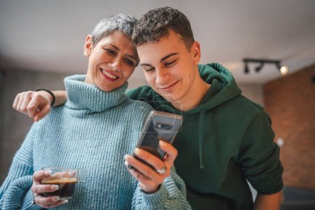 Téléchargez les photos : Adolescent garçon jeune homme et mature femme mère et fils prendre des photos selfie autoportraits à la maison - en image libre de droit