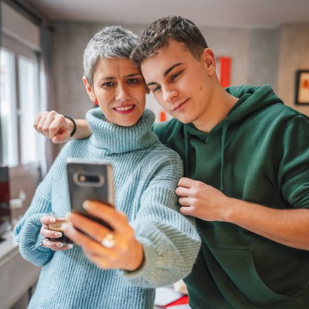 Téléchargez les photos : Adolescent garçon jeune homme et mature femme mère et fils prendre des photos selfie autoportraits à la maison - en image libre de droit