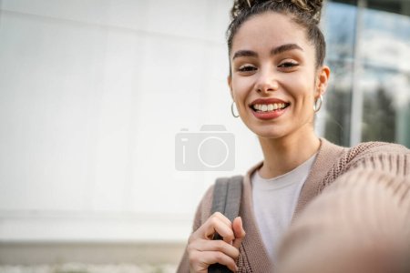 Eine junge erwachsene kaukasische Frau steht draußen posiert Selbstporträt Selfie glücklich zuversichtlich Lächeln in sonnigem Tag