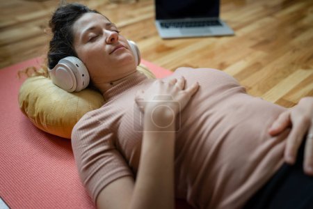 Photo for One woman adult caucasian female millennial using headphones for online guided meditation practicing mindfulness yoga with eyes closed on the floor at home real people self care concept copy space - Royalty Free Image
