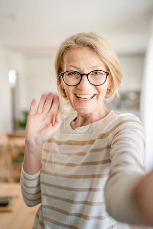Porträt einer reifen blonden kaukasischen Frau mit Brille zu Hause glücklich lächelnd in die Kamera guckend selbstbewusst Pullover in hellen Raum Benutzer generiert Inhalte Selbstporträt Selfie ugc Kopierraum