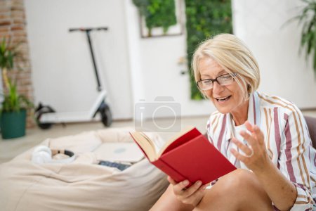 Foto de Una mujer madura caucásica mujer moderna en habitación luminosa leer libro en casa gafas de desgaste persona real copiar espacio - Imagen libre de derechos