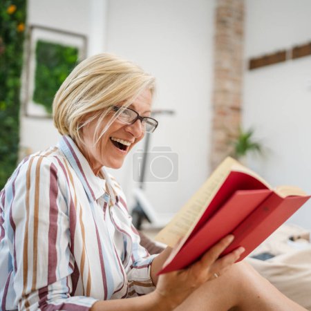 Photo for One woman mature caucasian female modern in bright room read book at home wear eyeglasses real person copy space - Royalty Free Image