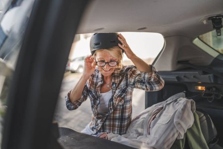 Photo for One mature blonde beautiful woman travel concept female take stuff belongings from the back of her car while moving or arrive to destination real people copy space - Royalty Free Image