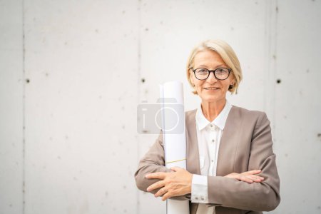 Téléchargez les photos : Portrait d'une femme d'affaires mature blonde caucasienne debout en plein air - en image libre de droit