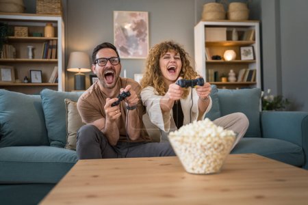 Adult couple man and woman caucasian husband and wife or boyfriend and girlfriend play console video games at home hold joystick controller have fun leisure joy and bonding concept copy space