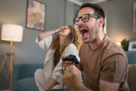 Photo for Adult couple man and woman caucasian husband and wife or boyfriend and girlfriend play console video games at home hold joystick controller have fun leisure joy and bonding concept copy space - Royalty Free Image