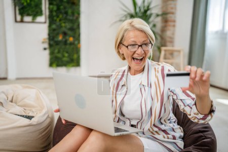 Photo for One mature senior woman sit at home use credit or debit card for online shopping browse internet stores buying stuff use laptop computer real people copy space - Royalty Free Image