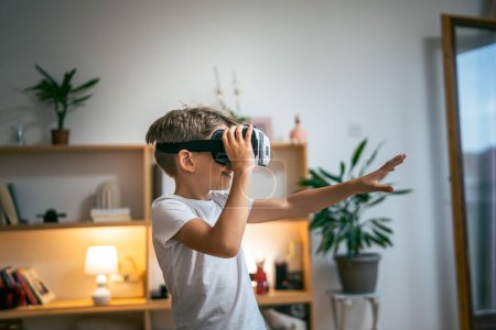 Foto de Niño varón caucásico niño en casa disfrutar de realidad virtual VR auriculares - Imagen libre de derechos