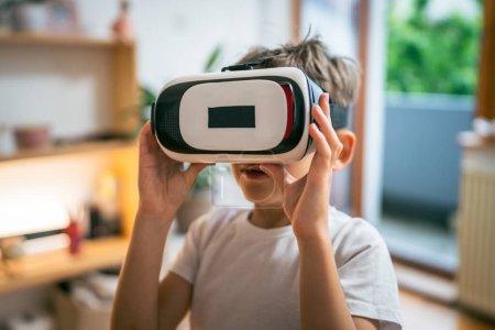 Téléchargez les photos : Garçon mâle caucasien enfant à la maison profiter réalité virtuelle VR casque - en image libre de droit