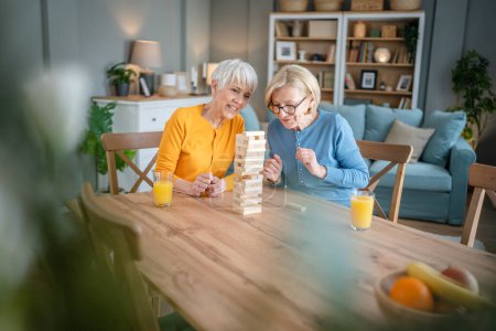 Foto de Dos mujeres mayores mujeres amigas o hermanas de la familia juegan juego de mesa de ocio en casa divertirse abuela pensionista pasar tiempo junto con su hija madura - Imagen libre de derechos