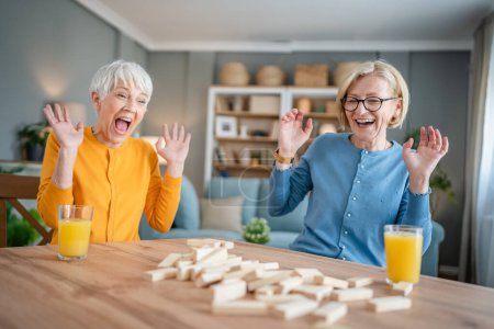 Téléchargez les photos : Deux femmes âgées femmes amies ou sœurs de la famille jouent jeu de société de loisirs à la maison ont plaisir retraité grand-mère passer du temps avec leur fille mature - en image libre de droit
