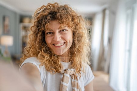 Téléchargez les photos : Portrait d'une femme caucasienne adulte à la maison sourire heureux cheveux bouclés - en image libre de droit