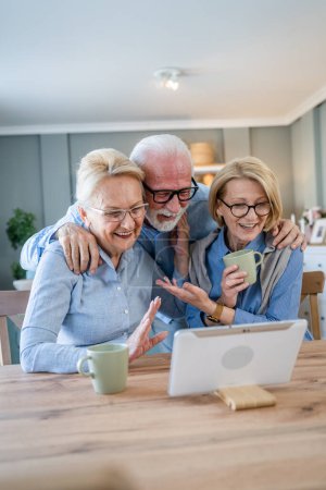 Photo for Group of people mature senior caucasian family or friends use digital tablet for video call at home real people copy space - Royalty Free Image
