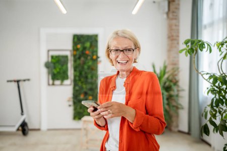 Foto de Retrato de una mujer caucásica rubia madura con gafas en casa u oficina sonrisa feliz mirando a la cámara con confianza copia espacio - Imagen libre de derechos