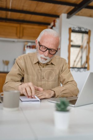 Photo for One senior caucasian man grandfather with beard and eyeglasses work on laptop use computer at home - Royalty Free Image