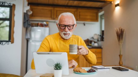 Foto de Un hombre mayor se sienta en casa en la cocina con una taza de té o café tomando un freno del trabajo o prepararse para la rutina diaria de la mañana persona real copiar espacio vida doméstica activo senior - Imagen libre de derechos