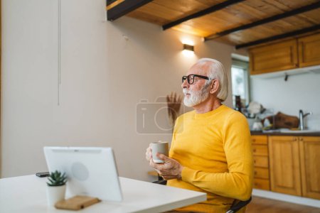 Foto de Un hombre mayor se sienta en casa en la cocina con una taza de té o café tomando un freno del trabajo o prepararse para la rutina diaria de la mañana persona real copiar espacio vida doméstica activo senior - Imagen libre de derechos