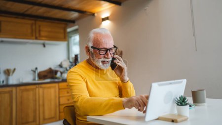 Téléchargez les photos : Un homme caucasien senior homme avec barbe grise assis dans la journée utiliser un téléphone intelligent mobile pour faire un travail d'espace de copie de conversation d'appel de la maison - en image libre de droit
