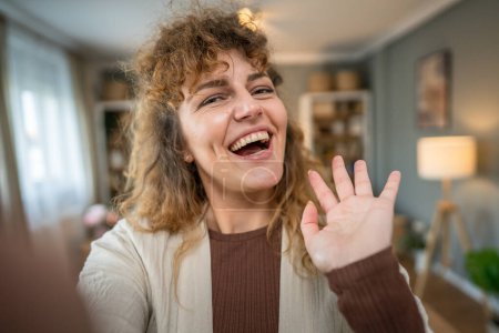 Foto de Una mujer caucásica mujer feliz seguro de pie interior en casa con el pelo rizado sonrisa persona real copia espacio autorretrato selfie UGC usuario contenido generado - Imagen libre de derechos
