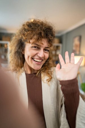 Foto de Una mujer caucásica mujer feliz seguro de pie interior en casa con el pelo rizado sonrisa persona real copia espacio autorretrato selfie UGC usuario contenido generado - Imagen libre de derechos