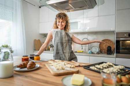 Téléchargez les photos : Une jeune femme caucasienne adulte heureuse porte un tablier dans la cuisine sourire - en image libre de droit