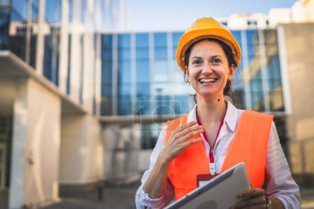 Photo for Architect woman female construction engineer stand outdoors wear protective helmet and west in front of modern building wall - Royalty Free Image