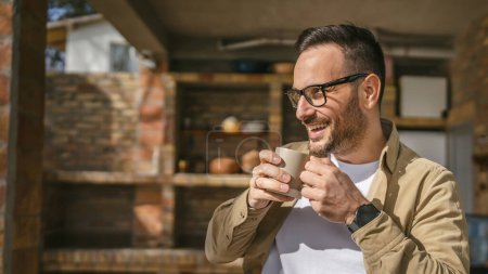 Photo for One adult caucasian man stand outdoor in front of his house in sunny morning or day enjoy cup of tea or coffee real people daily routine happy smile copy space - Royalty Free Image