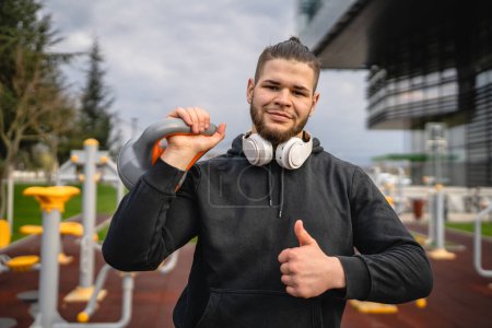 Photo for One man young caucasian male athlete stand outdoor in day posing with russian bell girya kettlebell weight real person copy space - Royalty Free Image