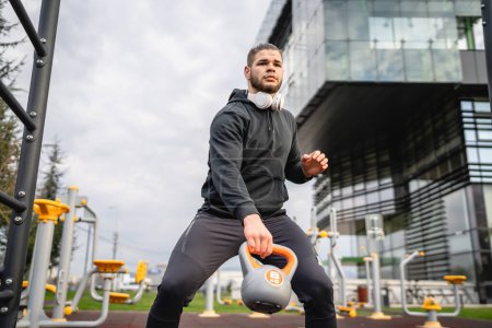 Photo for One man young caucasian male athlete stand outdoor in day training with russian bell girya kettlebell weight exercise real person copy space - Royalty Free Image