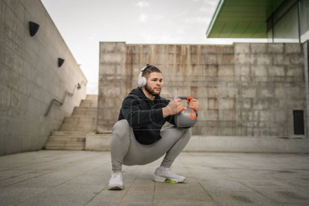 Photo for One man young caucasian male athlete stand outdoor in day training with russian bell girya kettlebell weight exercise real person copy space - Royalty Free Image