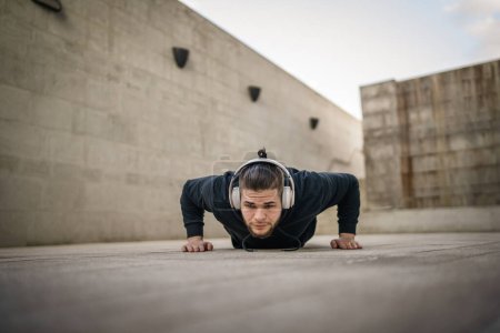 Foto de Un hombre joven adulto caucásico masculino entrenamiento al aire libre haciendo flexiones - Imagen libre de derechos
